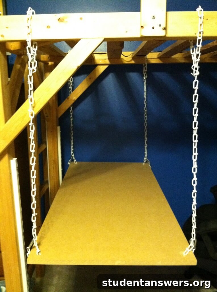 The hanging desk suspended by four chains from a loft bed frame, before stabilization.