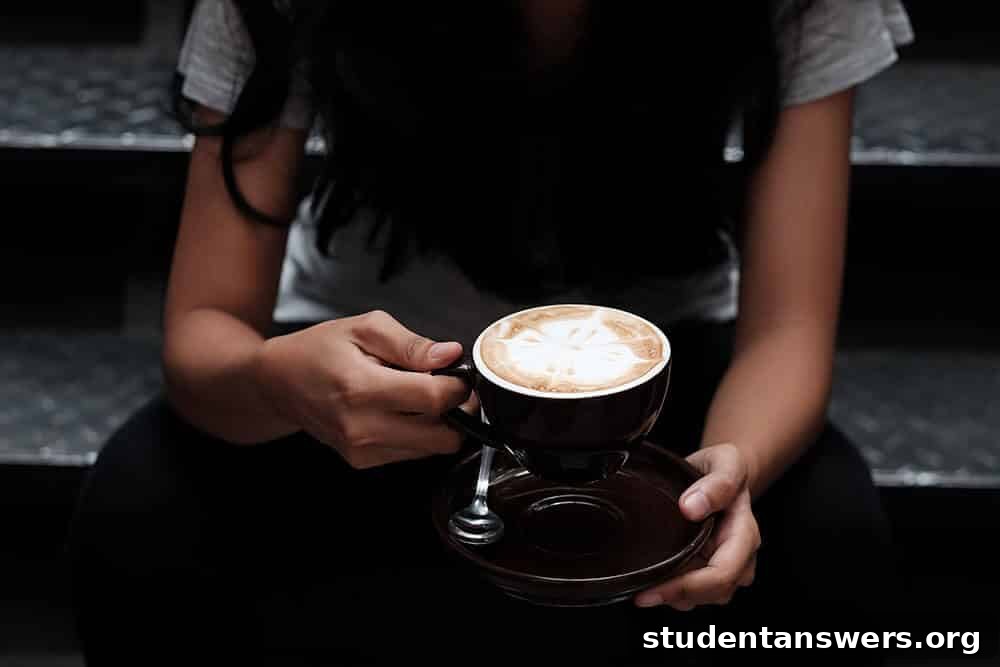 A person sitting at a cafe table with a decorative latte.