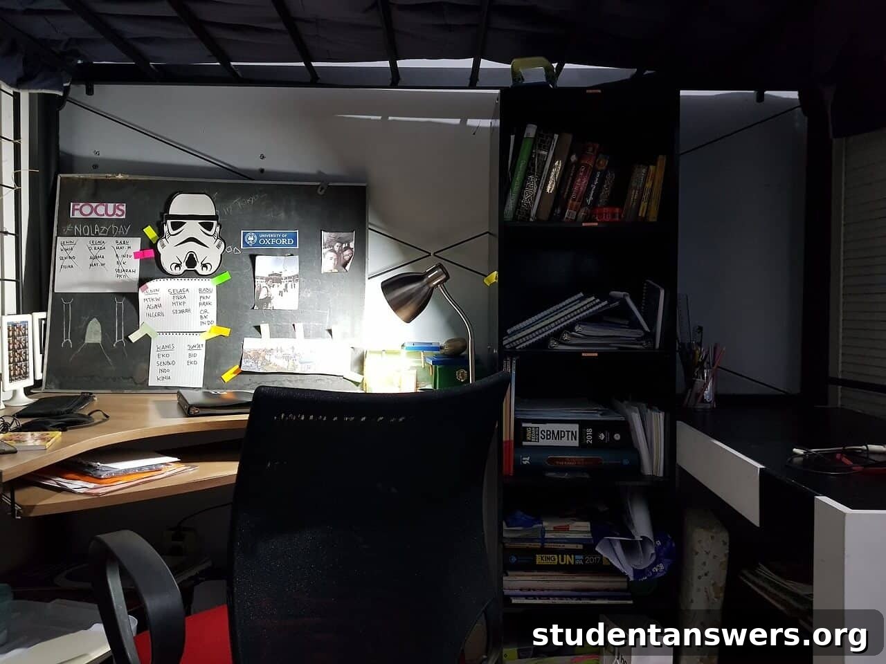 A cozy study desk and bookshelf situated underneath a lofted dorm bed.