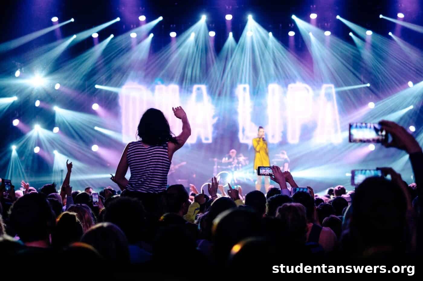 A large, engaged crowd at a concert with their hands in the air.