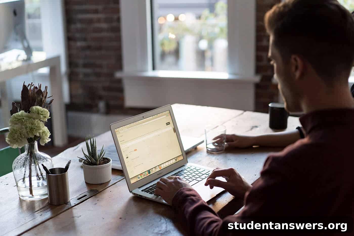 A person searching for a mentor on their laptop at a wooden desk
