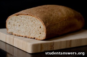 A beautiful, golden-brown homemade loaf of bread on a wooden cutting board