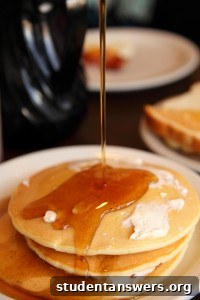 A perfect golden-brown pancake being flipped in a black frying pan.