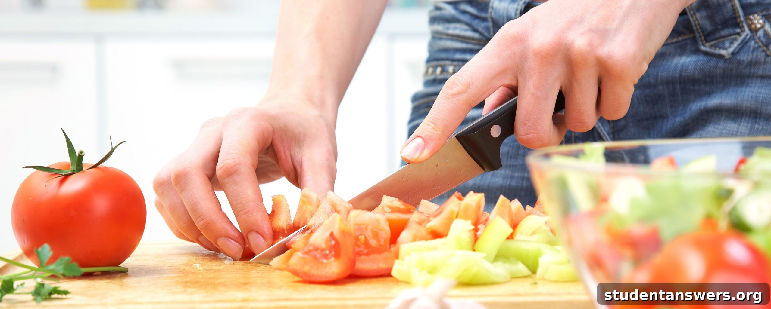 Student chopping fresh vegetables in a kitchen, preparing a healthy meal.