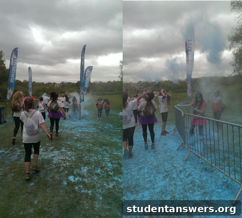 A participant being doused with bright pink color powder by a volunteer at a Dye Zone during the run.