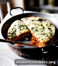 A layered Mexican vegetable tortilla bake with melted cheese on top