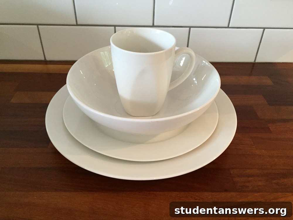 A clean, matching set of white student plates, bowls, and mugs